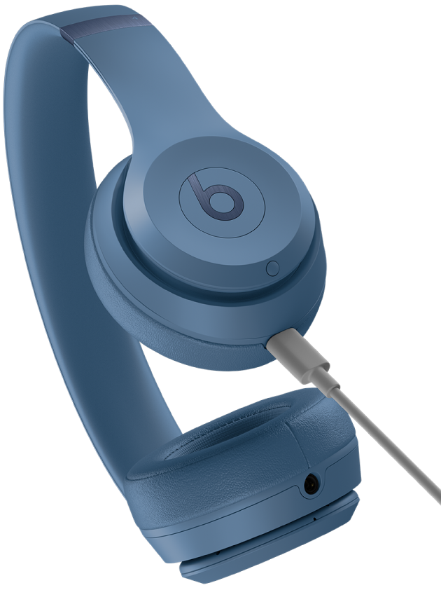 USB-C cable connected to the charging port on the Beats Solo 4 right earcup (below the system button).