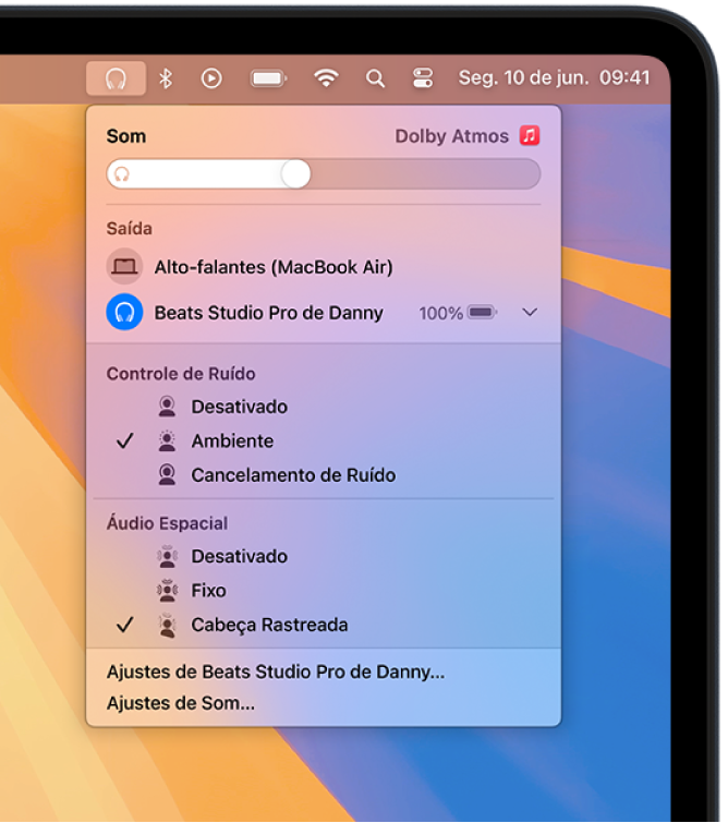O ícone Beats está selecionado acima à direita na barra de menus do Mac. Um menu mostra o dispositivo Beats Studio Pro com o modo Ambiente e Áudio Espacial com cabeça rastreada ativado.