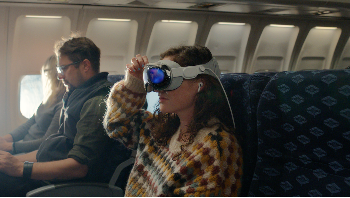 Eine Frau, die die Apple Vision Pro aufgesetzt hat und in den Ohren AirPods Pro trägt.