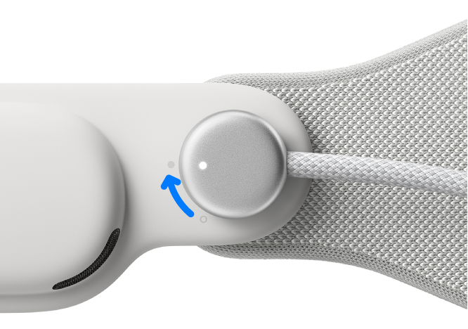 L’Apple Vision Pro avec le câble d’alimentation connecté à la sangle audio gauche. Une flèche montre la rotation du câble d’alimentation dans le sens des aiguilles d’une montre.
