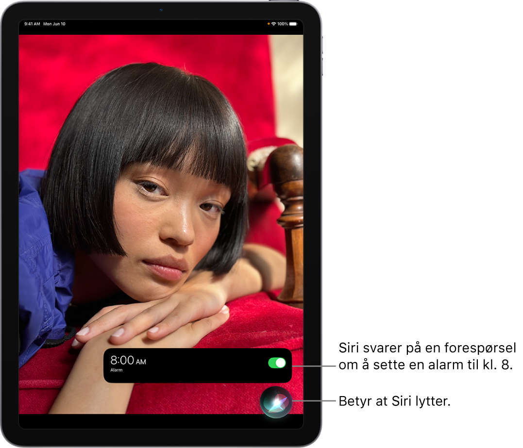 En iPad-skjerm. Nær bunnen av skjermen viser en varsling fra Klokke-appen at en alarm er satt på til klokken 08.00. Et symbol under varslingen viser at Siri er aktiv.