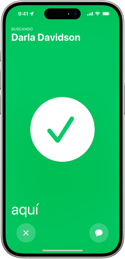 La pantalla del iPhone está en verde con una marca de verificación grande en el centro. El nombre de la persona que se está localizando está en la esquina superior izquierda, y la palabra “aquí” está en la esquina inferior izquierda para indicar que el encuentro se ha producido correctamente.