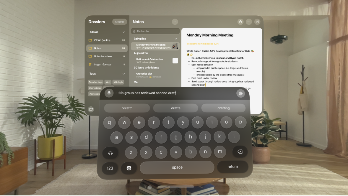 La vue d’un utilisateur sur l’Apple Vision Pro. L’app Notes est ouverte et une note est en cours de modification avec le clavier virtuel. L’aperçu du texte en cours de modification est visible en haut du clavier.