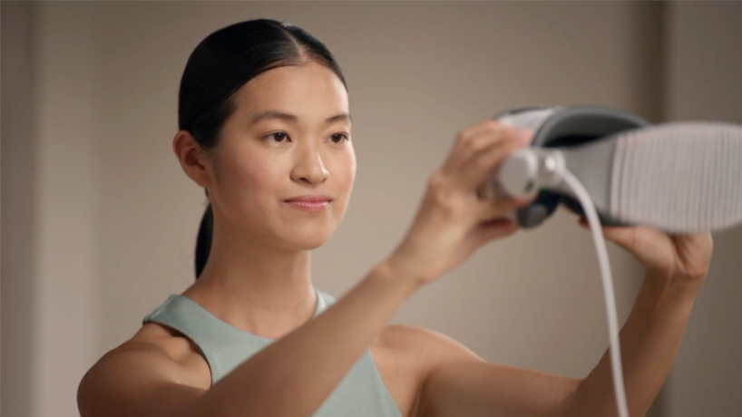 Une personne qui tient l’Apple Vision Pro devant elle à hauteur des yeux pour capturer son Persona.