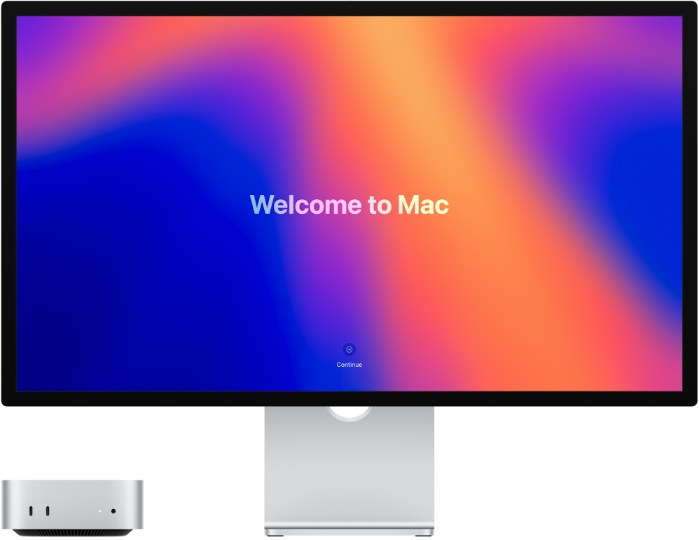 Ein Mac mini und ein Studio Display nebeneinander und auf dem Bildschirm ist „Willkommen beim Mac“ zu sehen.