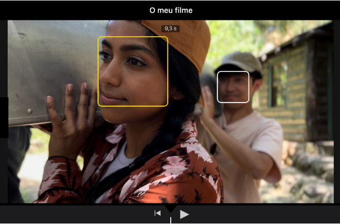 Um clip do modo Cinematográfico no visualizador, com uma caixa amarela sólida ao redor de um rosto indicando que o foco está bloqueado nesse objeto. Aparece uma caixa branca num objeto que não está focado.