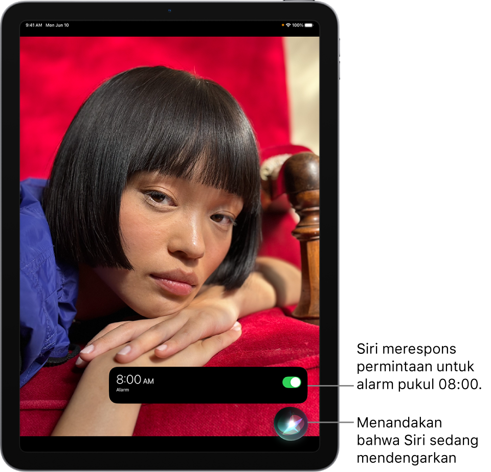 Layar iPad. Di dekat bagian bawah layar, pemberitahuan dari app Jam memperlihatkan bahwa alarm dinyalakan untuk pukul 08.00. Ikon di bawah pemberitahuan menandakan bahwa Siri sedang mendengarkan.