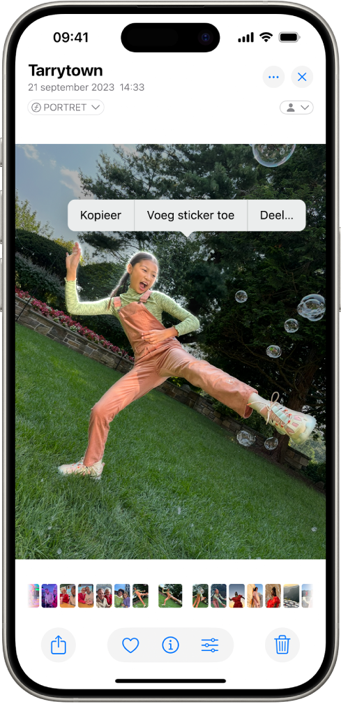 De Foto's-app is geopend met een foto van iemand. Deze persoon is geselecteerd en de optie 'Voeg sticker toe' is beschikbaar in het menu erboven.