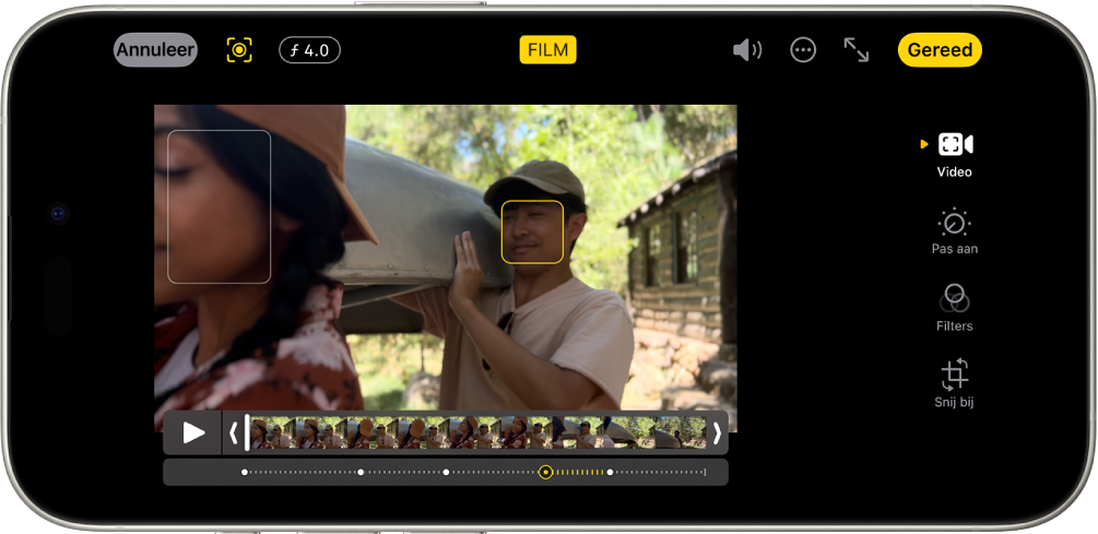 Het bewerkingsscherm van een filmmodusvideo. Linksboven in het scherm staan de annuleerknop, de knop voor de handmatige filmmodus en de knop voor de diepteaanpassing. Boven in het scherm is de knop 'Film' geselecteerd. Rechtsboven in het scherm staan de volumeknop, de knop 'Meer', de knop voor de schermvullende weergave en de knop 'Gereed'. De video staat in het midden van het scherm en er staat een kader rond het focusonderwerp. Onder de video staat de frameviewer met het punt in de video waar de focus naar een ander onderwerp wordt verplaatst. Aan de rechterkant van het scherm staan de bewerkingsknoppen, met van boven naar beneden: 'Video', 'Pas aan', 'Filters' en 'Snij bij'.