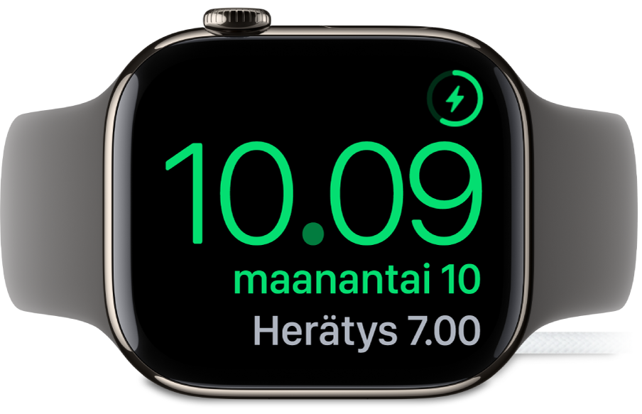 Apple Watch kyljellään ja yhdistettynä virtalähteeseen. Näytön oikeassa yläkulmassa on lataussymboli, sen alapuolella on nykyinen aika ja seuraavan herätyksen aika.