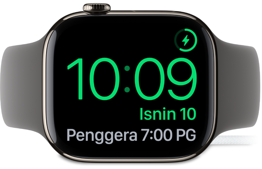 Apple Watch diletakkan di sisi dan bersambung ke pengecas, dengan skrin menunjukkan simbol mengecas di penjuru atas kanan, masa semasa di bawahnya dan masa penggera seterusnya.