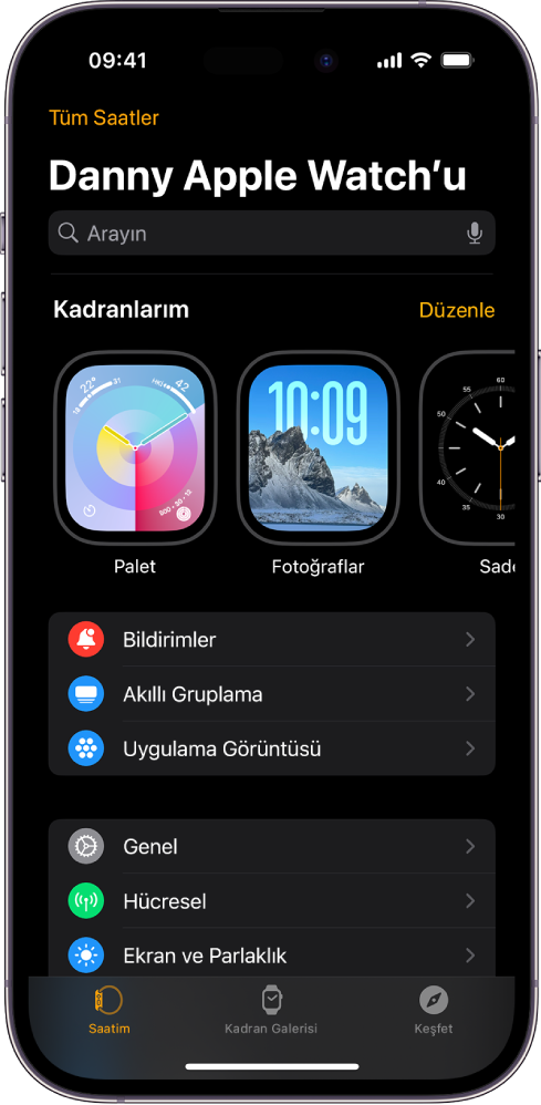 Üst tarafta saat kadranlarını ve altta ayarları gösteren Saatim ekranı açık olarak iPhone’daki Apple Watch uygulaması. Apple Watch uygulaması ekranının en altında üç sekme var: Soldaki sekme Apple Watch ayarlarını yapmak için gittiğiniz Saatim; yanındaki, kullanılabilir saat kadranlarını ve komplikasyonları keşfedebileceğiniz Kadran Galerisi ve diğeri, Apple Watch hakkında daha fazla bilgi edinebileceğiniz bir yer olan Keşfet sekmesi.