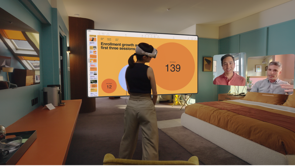 A person wearing Apple Vision Pro and having a FaceTime call. The tiles for others on the call are visible next to a shared screen.