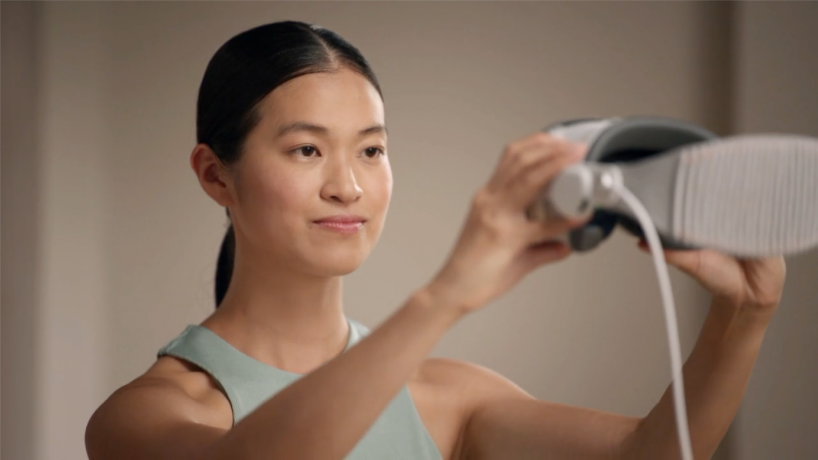 A person holding Apple Vision Pro in front of them at eye level to capture their Persona.