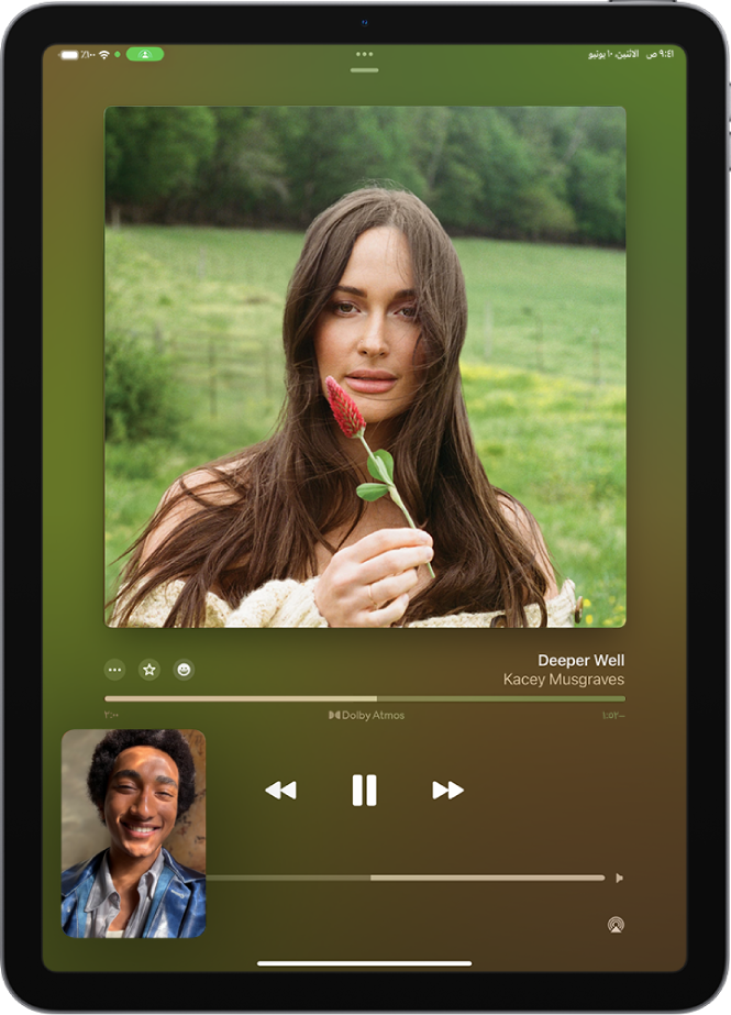 مكالمة فيس تايم تعرض جلسة مشاركة التشغيل، بها محتوى Apple Music تتم مشاركته بشكل متزامن مع الجميع في المكالمة. تظهر صورة الشخص الذي يشارك المحتوى في الجزء السفلي، وتظهر صورة الألبوم الذي تتم مشاركته في الجزء العلوي من الشاشة، وتظهر عناصر التحكم في التشغيل في أسفل صورة الألبوم.