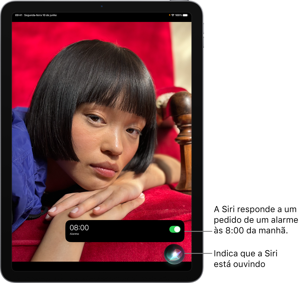 A tela de um iPad. Perto da parte inferior da tela, uma notificação do app Relógio mostra que um alarme está ativado para as 8 horas da manhã. Um ícone abaixo da notificação indica que a Siri está ouvindo.