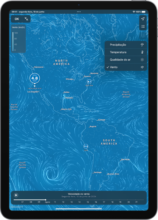 Um mapa de temperatura da área circundante preenche o ecrã do iPad. No canto superior direito, de cima para baixo, estão os botões “Localização atual” e “Localizações favoritas”. A opção “Menu sobreposto” está aberta e a opção “Vento” está selecionada. Na parte inferior está um cronograma. O botão “Ativar/desativar mapa em ecrã completo” e “Escala de sobreposição do mapa de vento” estão no canto superior esquerdo.