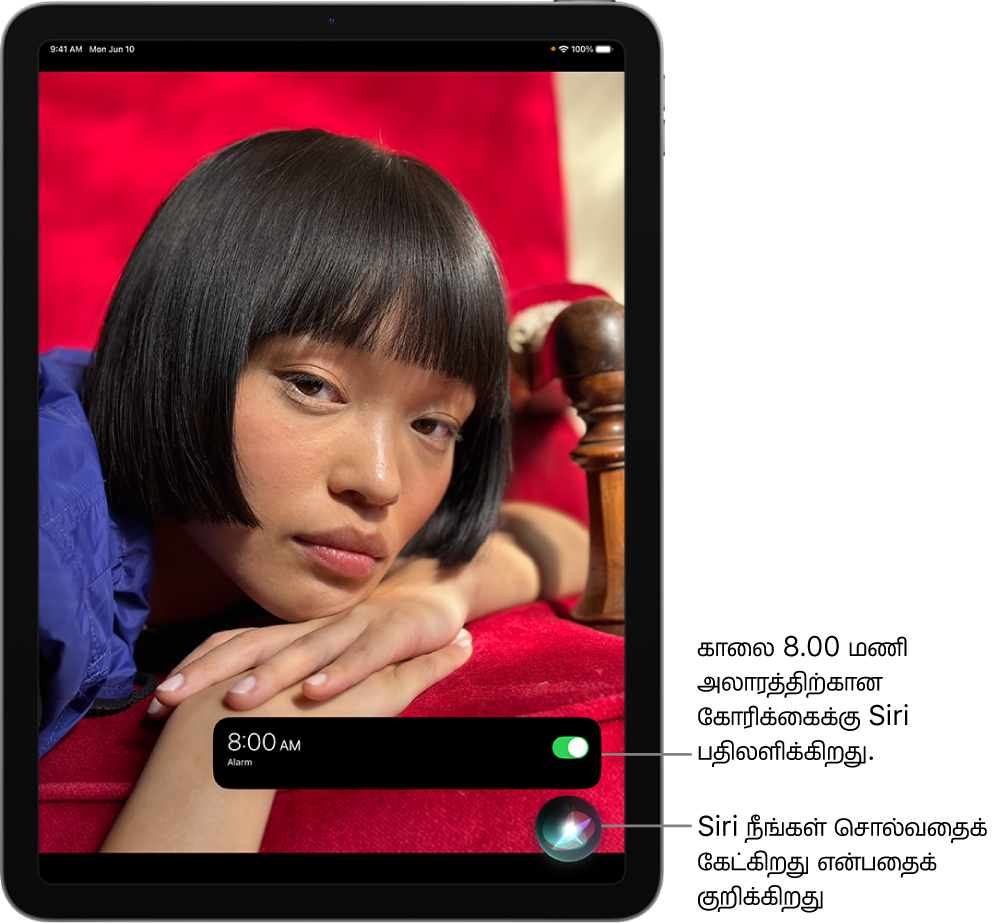 ஒரு iPad திரை. திரையின் கீழ்ப்பகுதிக்கு அருகில், காலை 8:00 மணிக்கு அலாரம் ஆன் செய்யப்பட்டிருப்பதை “கடிகாரம்” செயலியின் அறிவிப்பு காட்டுகிறது. அறிவிப்புக்குக் கீழே உள்ள ஐகான் Siri கேட்டுக்கொண்டிருக்கிறது என்பதைக் குறிக்கிறது.