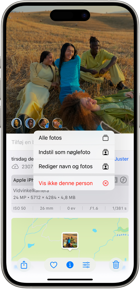 Den øverste halvdel af skærmen på iPhone viser et foto, der er åbent i appen Fotos. I det nederste venstre hjørne af fotoet er der spørgsmålstegn ved siden af personerne og kæledyrene, der vises på fotoet. Et spørgsmålstegn er valgt, og en menu med muligheder omfatter fra øverst til nederst Giv denne person et navn, Alle fotos, Indstil som nøglefoto, Rediger navn og fotos, og Vis mindre med denne person.