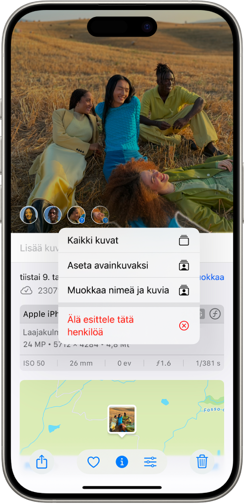iPhonen näytön yläosassa on kuva auki Kuvat-apissa. Kuvan vasemmassa alakulmassa on kysymysmerkkejä kuvassa näkyvien henkilöiden ja lemmikkien vieressä. Kysymysmerkki näkyy valittuna ja valikon vaihtoehtoihin kuuluvat ylhäältä alaspäin Nimeä tämä henkilö, Kaikki kuvat, Tee avainkuva, Muokkaa nimeä, Kuvat sekä Esittele tätä henkilöä vähemmän.