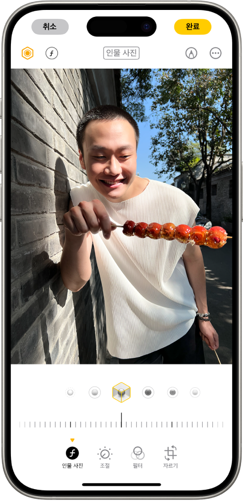 인물 사진의 편집 화면. 사진은 화면 중앙에 있고 사진 아래에는 인물 사진 조명 효과 옵션이 있음. 스튜디오 조명을 선택함. 그 아래에는 효과 수준을 조절하는 슬라이더가 있음. 화면 하단에 왼쪽에서 오른쪽으로 인물 사진 모드, 조절, 필터 및 자르기 버튼이 나열됨. 인물 사진 모드 버튼을 선택함.