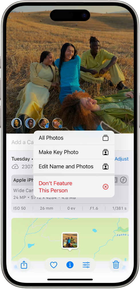 iPhone ekrāna augšējā daļā ir redzams fotoattēls, kas atvērts lietotnē Photos. Fotoattēla apakšējā kreisajā stūrī blakus cilvēkiem un mājdzīvniekiem, kas ir redzami fotoattēlos, ir jautājuma zīmes. Tiek atlasīta jautājuma zīme, un opciju izvēlnē no augšas uz leju ir iekļauts Name This Person, All Photos, Make Key Photo, Edit Name and Photos un Feature This Person Less.