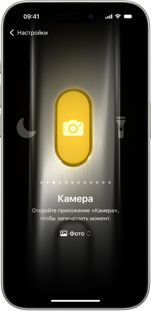 Экран настройки кнопки действия. В качестве выполняемого действия выбрана Камера. Другие функции указаны слева и справа от Камеры, например «Не беспокоить» и фонарик. Под значками функций расположены точки, которых можно касаться, чтобы выбрать другое действие. Под выбранной функцией (Камера) расположено меню с настройками Камеры, которого можно коснуться, чтобы назначить функцию кнопке действия.