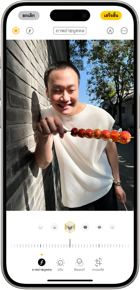 หน้าจอแก้ไขของภาพถ่ายบุคคล รูปภาพอยู่ตรงกึ่งกลางของหน้าจอ และด้านล่างรูปภาพคือตัวเลือกการจัดแสงภาพถ่ายบุคคล แสงไฟสตูดิโอถูกเลือกอยู่ ถัดลงมาเป็นแถบเลื่อนสำหรับปรับระดับเอฟเฟ็กต์ ด้านล่างสุดของหน้าจอโดยเรียงจากซ้ายไปขวา คือปุ่มภาพถ่ายบุคคล ปุ่มปรับ ปุ่มฟิลเตอร์ และปุ่มครอบตัด ปุ่มภาพถ่ายบุคคลถูกเลือกอยู่