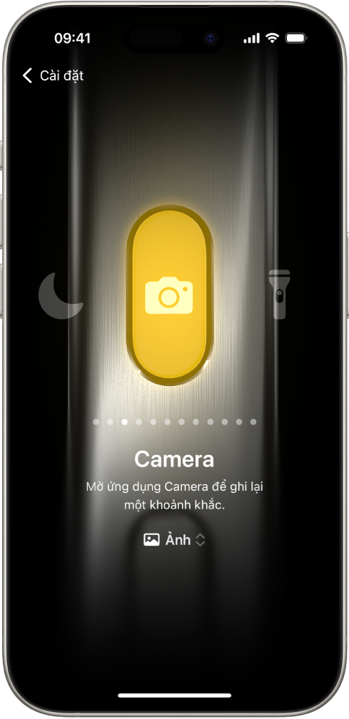 Màn hình để tùy chỉnh nút Tác vụ. Camera là tác vụ được chọn. Các tính năng khác xuất hiện ở bên phải và bên trái của camera, bao gồm Không làm phiền và Đèn pin. Bên dưới các tác vụ là các dấu chấm mà bạn có thể chạm vào để chuyển đổi sang một tác vụ khác. Bên dưới tác vụ được chọn, Camera, là một menu gồm các tùy chọn Camera mà bạn có thể chạm vào để chỉ định cho nút Tác vụ.