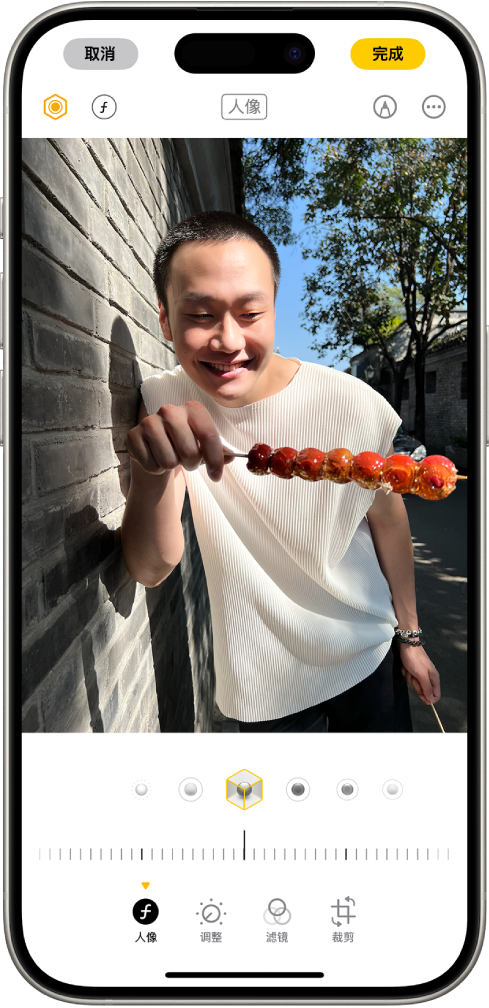 人像的“编辑”屏幕。照片位于屏幕中央,照片下方是“人像光效”选项。“摄影室灯光”已选中。其下方是用于调整效果级别的滑块。屏幕底部从左到右依次为“人像”、“调整”、“滤镜”和“裁剪”按钮。“人像”按钮已选中。