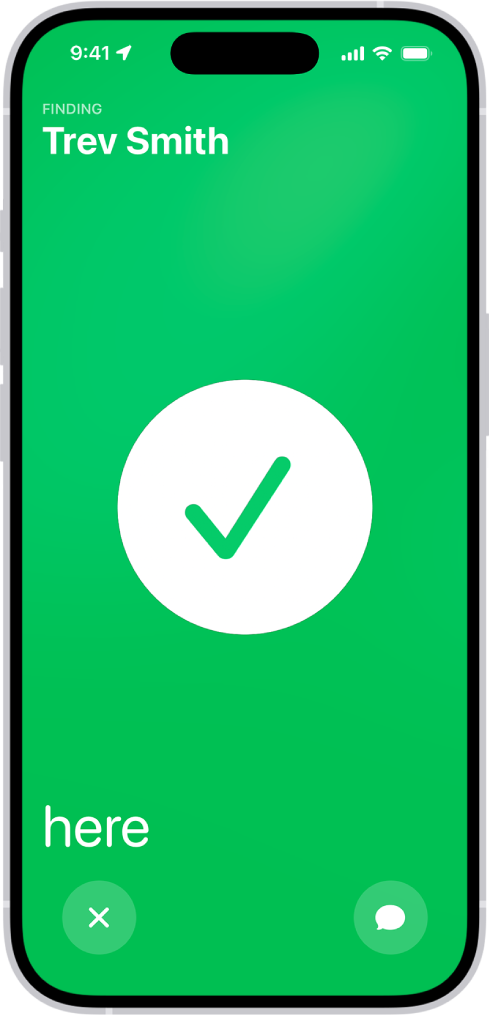 The iPhone screen is green with a big checkmark in the middle of it. The name of the person being located is in the top-left corner, and the word “here” is in the bottom-left corner, indicating that the meetup was successful.