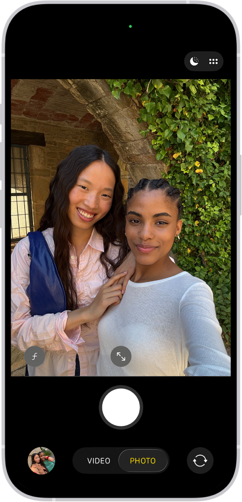 「写真」モードの「カメラ」画面。カメラの枠内で、被写体がセルフィーを撮っています。