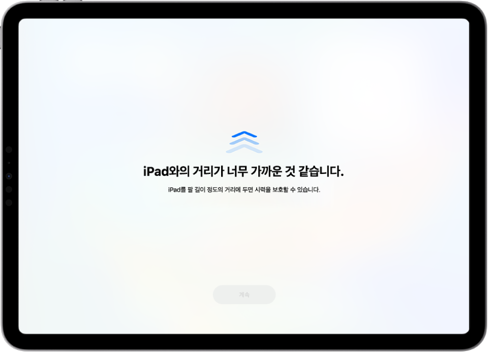 iPad를 너무 가까이 들고 있으며 시력을 보호하기 위해 더 멀리 두어야 한다고 표시하는 화면 경고. 경고는 화면을 가려서 계속 진행하지 못하게 함. iPad를 안전한 거리까지 이동하면 계속 버튼이 활성화됨.