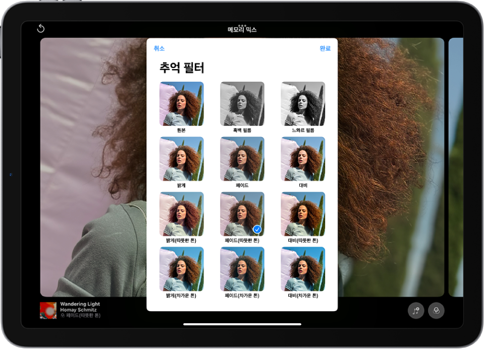 화면 중앙에서 추억이 재생됨. 화면 하단에 왼쪽에서 오른쪽으로 메모리 믹스, 사진 및 동영상 버튼이 나열됨. 오른쪽 상단에는 음량, 더 보기 및 닫기 버튼이 있음. 왼쪽 상단에는 추억의 제목과 재생 중인 노래 및 아티스트의 이름이 있음.