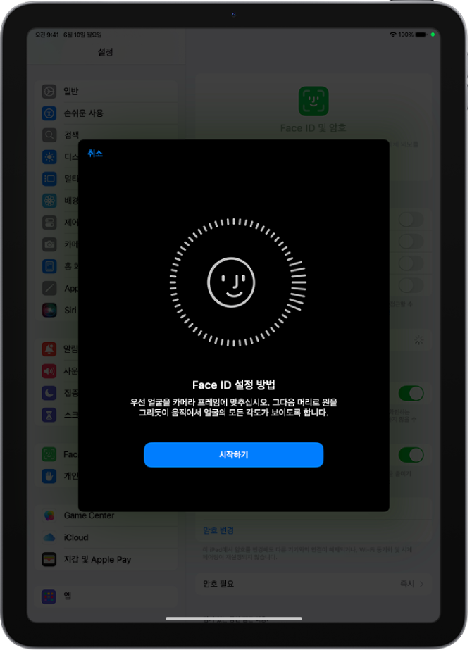 Face ID 인식 설정 화면. 원형 프레임 안에 웃는 얼굴이 있는 화면이 표시됨. 아래에는 사용자에게 천천히 머리를 움직여 원을 완성하라는 지침이 표시된 텍스트가 있음. 화면의 하단 근처에 시작하기 버튼이 나타남.