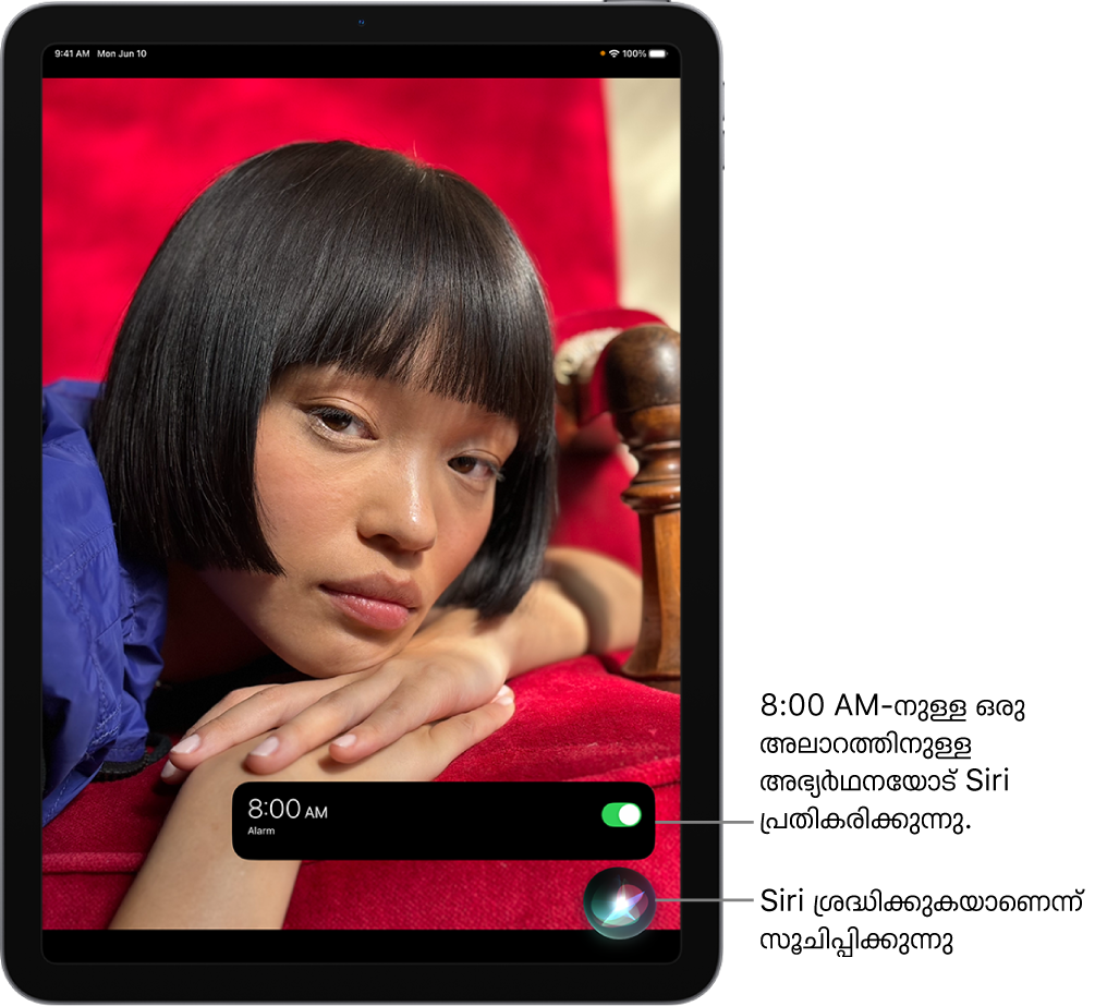 ഒരു iPad സ്ക്രീൻ. സ്ക്രീനിന്റെ താഴെ, ‘ക്ലോക്ക്’ ആപ്പിൽ നിന്നുള്ള ഒരു അറിയിപ്പ് രാവിലെ 8:00-ന് ഒരു അലാറം ഓണാക്കിയതായി കാണിക്കുന്നു. അറിയിപ്പിന്റെ താഴെയുള്ള ഒരു ഐക്കൺ Siri കേൾക്കുന്നുണ്ടെന്ന് സൂചിപ്പിക്കുന്നു.