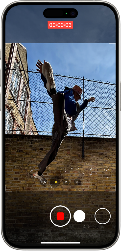 L’écran « Appareil photo » en mode Photo. Le sujet remplit le centre de l’écran, à l’intérieur du cadre de l’appareil photo. En bas de l’écran, une vidéo QuickTake est lancée, ce qui se traduit par un glissement du bouton Obturateur vers la droite. Le minuteur vidéo se trouve en haut de l’écran.