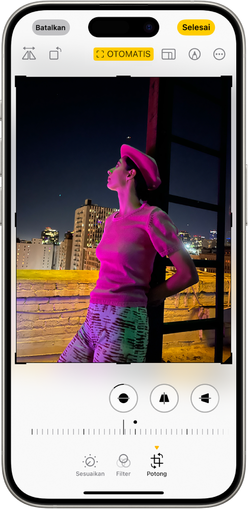 Layar Edit dengan foto di tengah. Di bagian bawah layar, dari kiri ke kanan, terdapat tombol Sesuaikan, Filter, dan Potong. Tombol Potong dipilih dan terdapat penggeser untuk menyesuaikan peningkatan geometri.