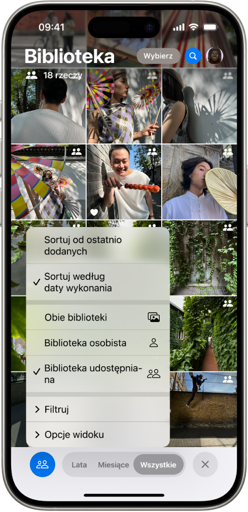 Udostępniana biblioteka zdjęć w iCloud wyświetlana w aplikacji Zdjęcia. W lewym dolnym rogu widoczny jest zaznaczony przycisk Biblioteka udostępniana. Na liście bibliotek wybrana jest biblioteka udostępniana. Wszystkie zdjęcia wyświetlane w bibliotece są oznaczone w prawym górnym rogu plakietką biblioteki udostępnianej.