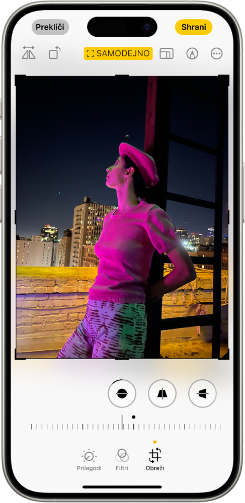 Zaslon Uredi s fotografijo na sredini. Na dnu zaslona so od leve proti desni gumbi Prilagodi, Filtri in Obreži. Izbran je gumb Obreži in na voljo je drsnik za prilagoditev izboljšav geometrije.