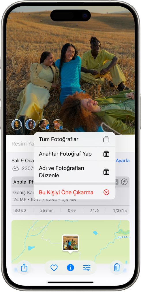 iPhone ekranının üst yarısında, Fotoğraflar uygulamasında açılmış bir fotoğraf gösteriliyor. Fotoğrafın sol alt köşesinde, fotoğrafta görünen kişilerin ve evcil hayvanların yanında soru işaretleri var. Bir soru işareti seçiliyor ve bir seçenek menüsünde yukarıdan aşağıya şunlar gösteriliyor: Bu Kişiyi Adlandırın, Tüm Fotoğraflar, Anahtar Fotoğraf Yap, Adı ve Fotoğrafları Düzenle ve Bu Kişiyi Daha Az Öne Çıkar.