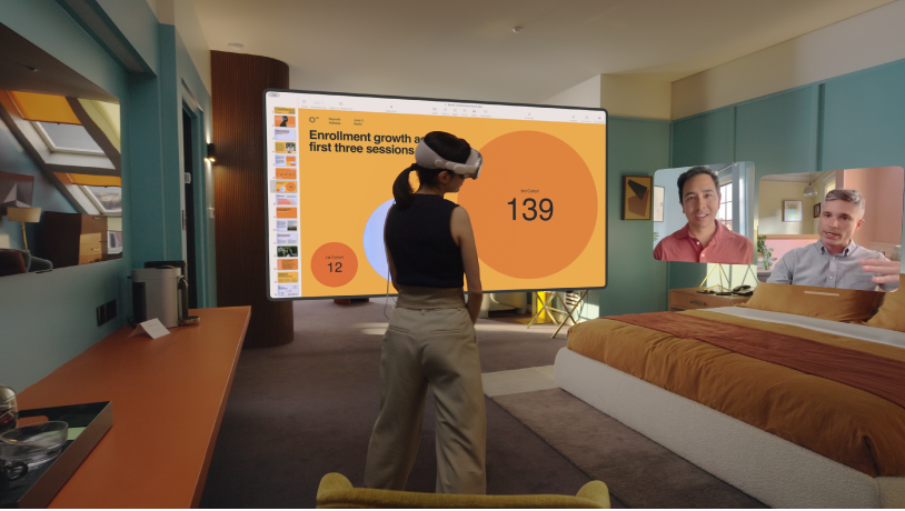 Una persona che indossa Apple Vision Pro durante una chiamata FaceTime. I riquadri degli altri partecipanti alla chiamata sono visibili accanto a uno schermo condiviso.