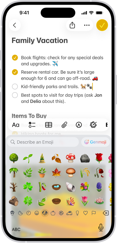Catatan terbuka di app Catatan di bagian atas layar, dan papan ketik emoji terbuka di bagian bawah layar.