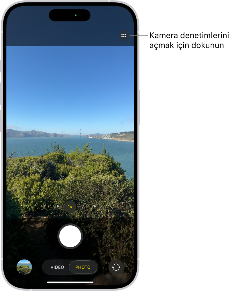 Kamera, Fotoğraf modunda açık. Kamera Denetimleri düğmesi sağ üst köşede. Fotoğraf ve Video Görüntüleyici düğmesi sol alt köşede. Resim Çek düğmesi alt ortada ve Arkaya Bakan Kamerayı Seçme düğmesi sağ alt köşede.