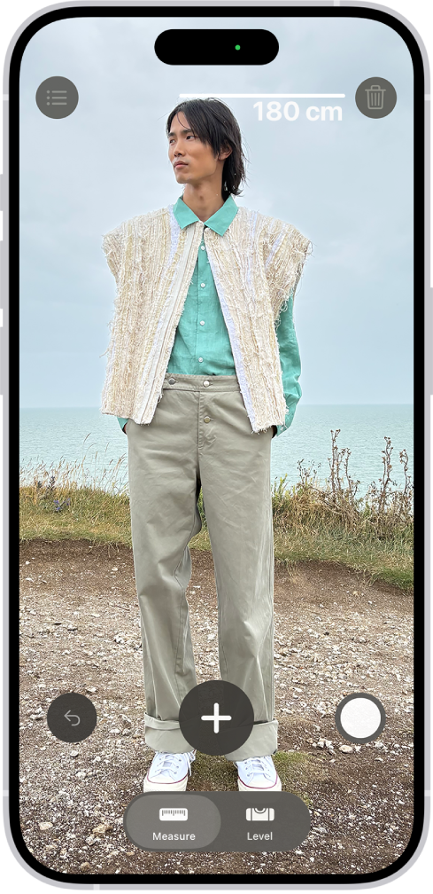 “测距仪” App 中正在测量一个人的身高,身高测量值显示在此人头顶。右下角附近的“拍照”按钮用于给测量结果拍照。绿色“相机使用中”指示器显示在顶部。