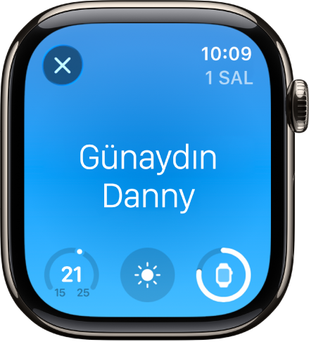 Uyanma ekranını gösteren Apple Watch. En üstte Günaydın sözcükleri görünüyor. Sıcaklık, hava durumu ve pil düzeyi alt tarafta.