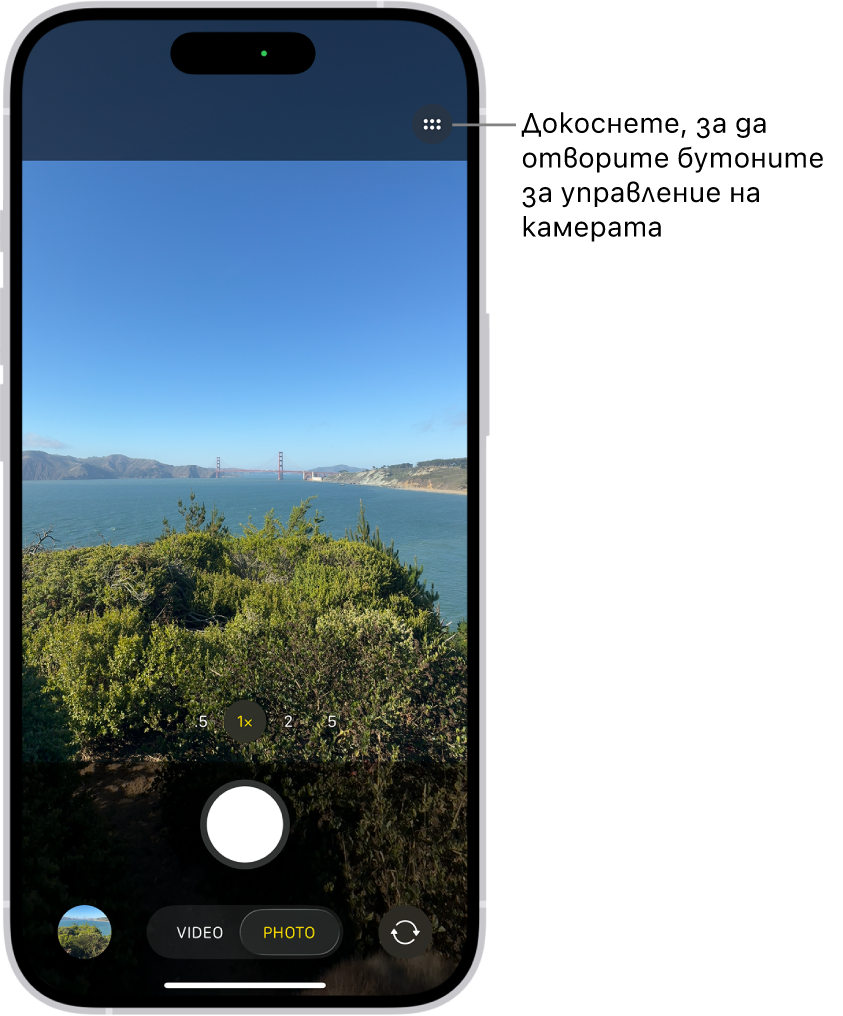 Приложението Камера е отворено в режим Снимка. Бутонът за Управление на камерата е в горния десен ъгъл. Бутонът за преглед на снимки и видео в долния ляв ъгъл. Бутонът за снимане е долу в центъра, а бутонът за превключване на камерите е в долния десен ъгъл.