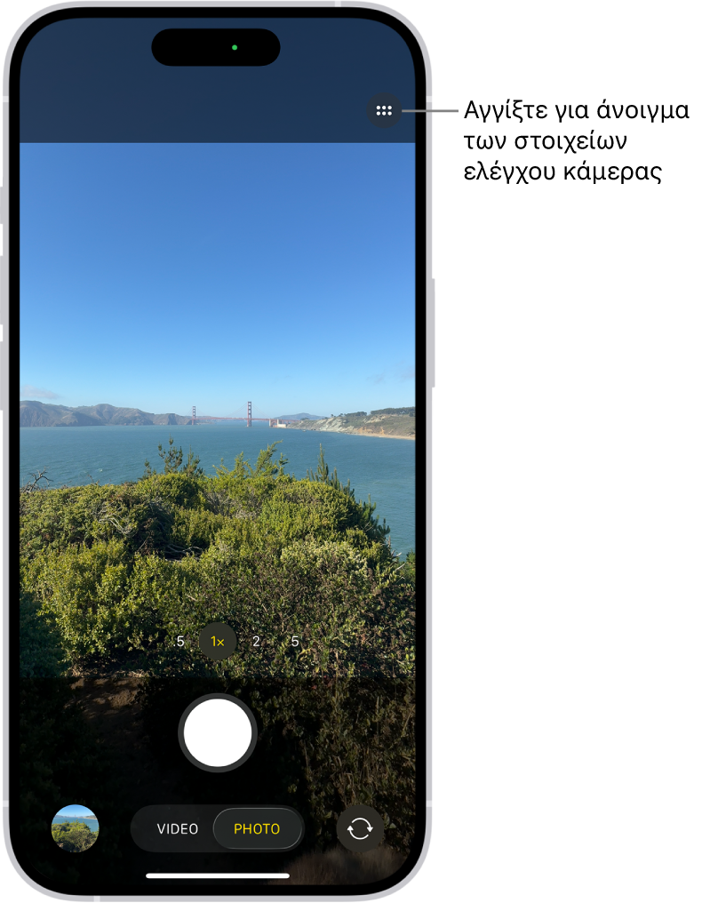 Η Κάμερα είναι ανοιχτή στη λειτουργία Φωτογραφίας. Το κουμπί «Στοιχεία ελέγχου Κάμερας» βρίσκεται στην πάνω δεξιά γωνία. Η Προβολή φωτογραφιών και βίντεο βρίσκεται στην κάτω αριστερή γωνία. Το κουμπί Λήψης φωτογραφίας βρίσκεται κάτω στο κέντρο και το κουμπί Επιλογέα πίσω κάμερας βρίσκεται στην κάτω δεξιά γωνία.