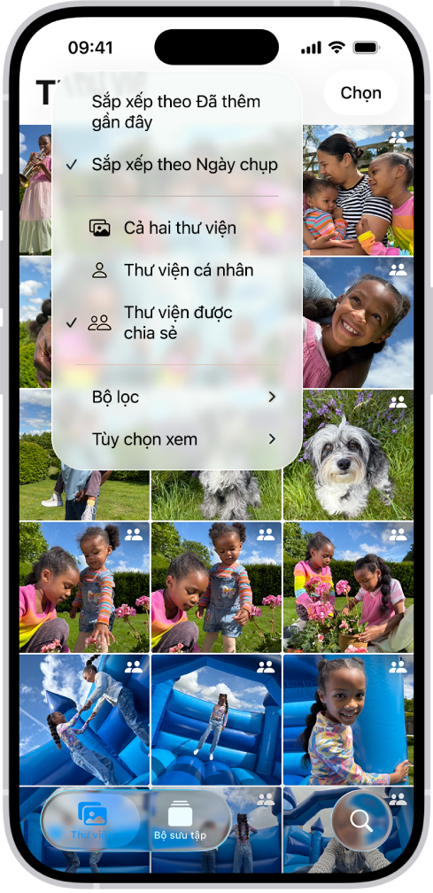 Một Thư viện ảnh được chia sẻ iCloud trong ứng dụng Ảnh. Nút Thư viện được chia sẻ ở góc dưới cùng bên trái được chọn và Thư viện được chia sẻ được chọn trong danh sách các tùy chọn thư viện. Tất cả ảnh được hiển thị trong thư viện đều có biểu tượng thư viện được chia sẻ ở góc trên cùng bên phải.