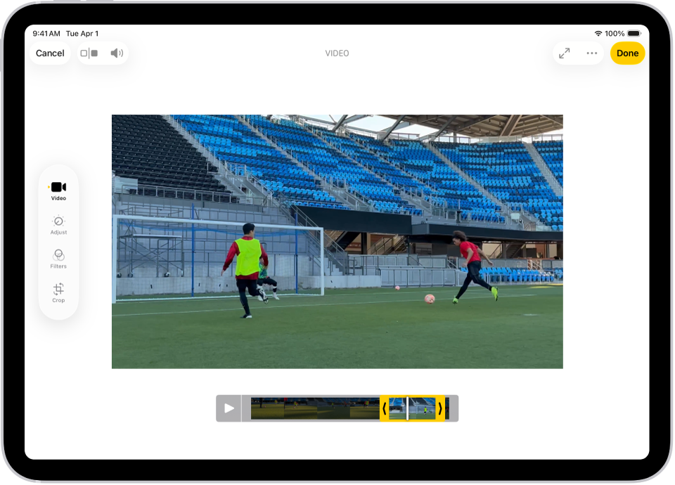 Layar Edit di app Foto dengan video diputar di pusat. Penampil bingkai video terdapat di bagian bawah video dan garis kuning terdapat di sekitar bingkai yang dipilih untuk disertakan dalam video yang dipangkas. Di sisi kiri layar terdapat tombol Video, Sesuaikan, Filter, dan Potong; tombol Video dipilih.